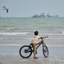 A gull flies overhead as a boy stands with his bicycle on a beach overlooking commercial vessels anchored in the Strait of Hormuz off Bandar Abbas, Iran, Monday, Sept. 7, 2026. (AP Photo/Vahid Salemi, File)(AP Photo/Vahid Salemi)