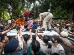 Several supporters climb atop a police vehicle carrying AISA leader Neha Bora after she was detained during a protest march by members of AISA and other student organisations demanding the resignation of CEC Gyanesh Kumar.(Sanchit Khanna/HT Photos)