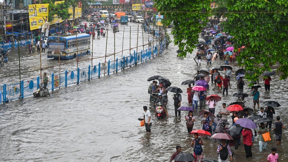 Commuters wade throught waterlogged roads in Kolkata under their umbrellas as rains continue to lash the city of joy since last night ahead of the state's biggest festival Durga Puja.