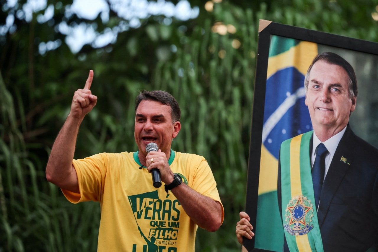 Brazilian presidential candidate Flávio Bolsonaro campaigning last month next to a portrait of his father, former President Jair Bolsonaro, in Goiânia, Brazil. Brazilian presidential candidate Flávio Bolsonaro campaigning last month next to a portrait of his father, former President Jair Bolsonaro, in Goiânia, Brazil.