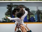 A demonstrator jumps out of a bus window broken by detained protesters during a protest against the alleged assault of female protesters and journalists by Delhi Police and demand the resignation of CEC Gyanesh Kumar(REUTERS)