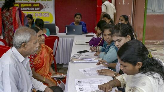 Booth Level Officers (BLOs) verify voter details during the special intensive revision (SIR) of electoral rolls at a special campaign weekend organised by Shivamogga Municipal Corporation, in Shivamogga. (PTI FILE)