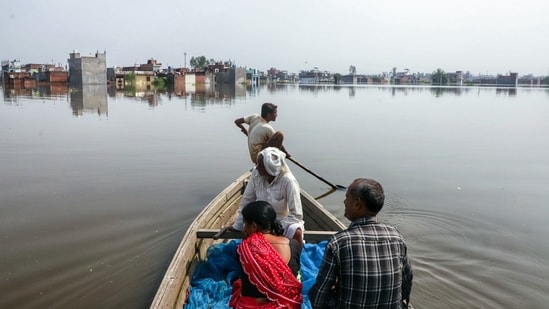 Local boatmen and rescue teams transport stranded residents to safety from the flood-affected Faizullaganj area due to flooding in the Gomti River.