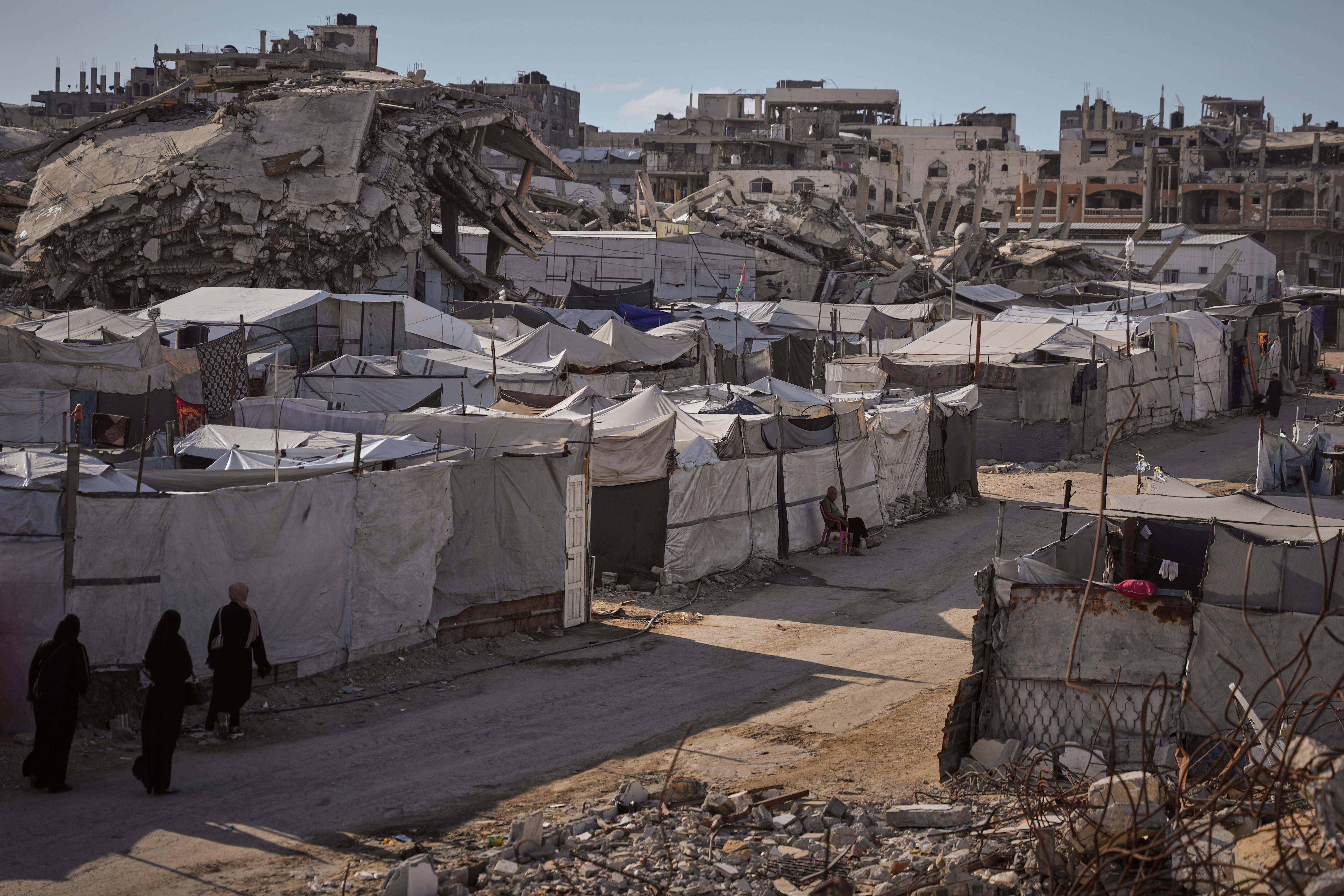 Palestinians walk along a street lined with tents sheltering displaced people and buildings destroyed by Israeli military strikes during the Israel-Hamas war in Gaza City, Tuesday, Oct. 6, 2026. (AP Photo/Abdel Kareem Hana) Palestinians walk along a street lined with tents sheltering displaced people and buildings destroyed by Israeli military strikes during the Israel-Hamas war in Gaza City, Tuesday, Oct. 6, 2026. (AP Photo/Abdel Kareem Hana)