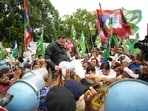 RJD National Working President and Bihar Assembly LoP Tejashwi Yadav climbs over a barricade as security personnel try to stop him during a protest march towards Lok Bhawan, 