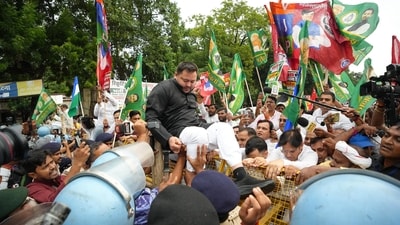 RJD National Working President and Bihar Assembly LoP Tejashwi Yadav climbs over a barricade as security personnel try to stop him during a protest march towards Lok Bhawan, (ANI) RJD National Working President and Bihar Assembly LoP Tejashwi Yadav climbs over a barricade as security personnel try to stop him during a protest march towards Lok Bhawan, (ANI)