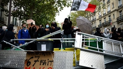 A protester holds a French flag behind a barricade to block the Boulevard Saint-Germain during a blockade of Sciences Po university in Paris as part of nationwide student protests demanding better school conditions. (Reuters)