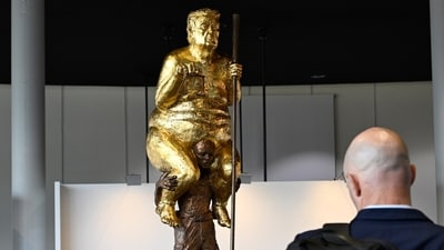 Visitors looks at a sculpture titled "The Orange Plague" by Danish artist Jens Galschiot, depicting US President Donald Trump. (AP Photo/Pascal Bastien)
