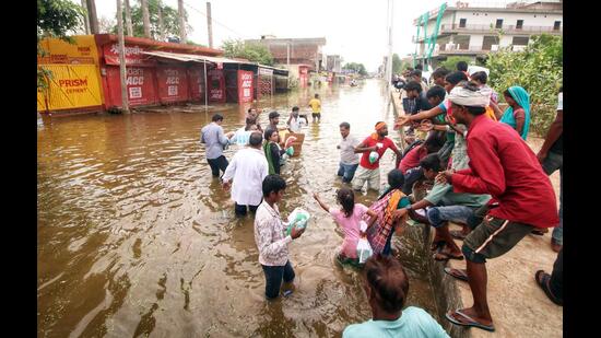 Residents of Faizullaganj area gather to collect water and other essential food supplies as floodwaters inundated their locality, in Lucknow on Wednesday. (ANI Photo)