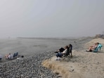 People sit (R) on what remains of an eroded beach as work continues on a sand replenishment project nearby along the Pacific Ocean shoreline in Oceanside, California. 