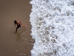 A child runs from the water as large waves break on the shore on Huntington Beach, southern California.