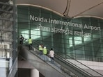 People stand on an escalator as they enter Noida International Airport (NIA) during a media visit to the project site, in Noida.(REUTERS)