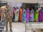 Bypoll election results LIVE: A security official keeps vigil as people wait in a queue at a polling station on the day of voting in the Madurantakam Assembly bypolls, in Chengalpattu district, Tamil Nadu.(PTI)