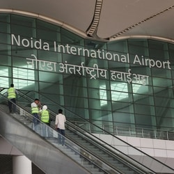 People stand on an escalator as they enter Noida International Airport (NIA) during a media visit to the project site, in Noida.