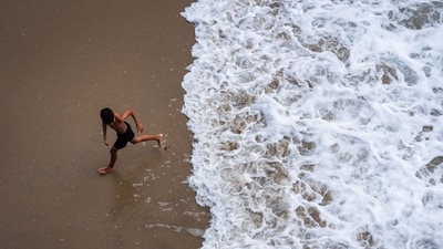 A child runs from the water as large waves break on the shore on Huntington Beach, southern California.
