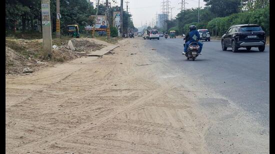 A resident of Sector 46, said the road shoulders remained covered in dust, while ongoing roadside work had added to the inconvenience. (HT)