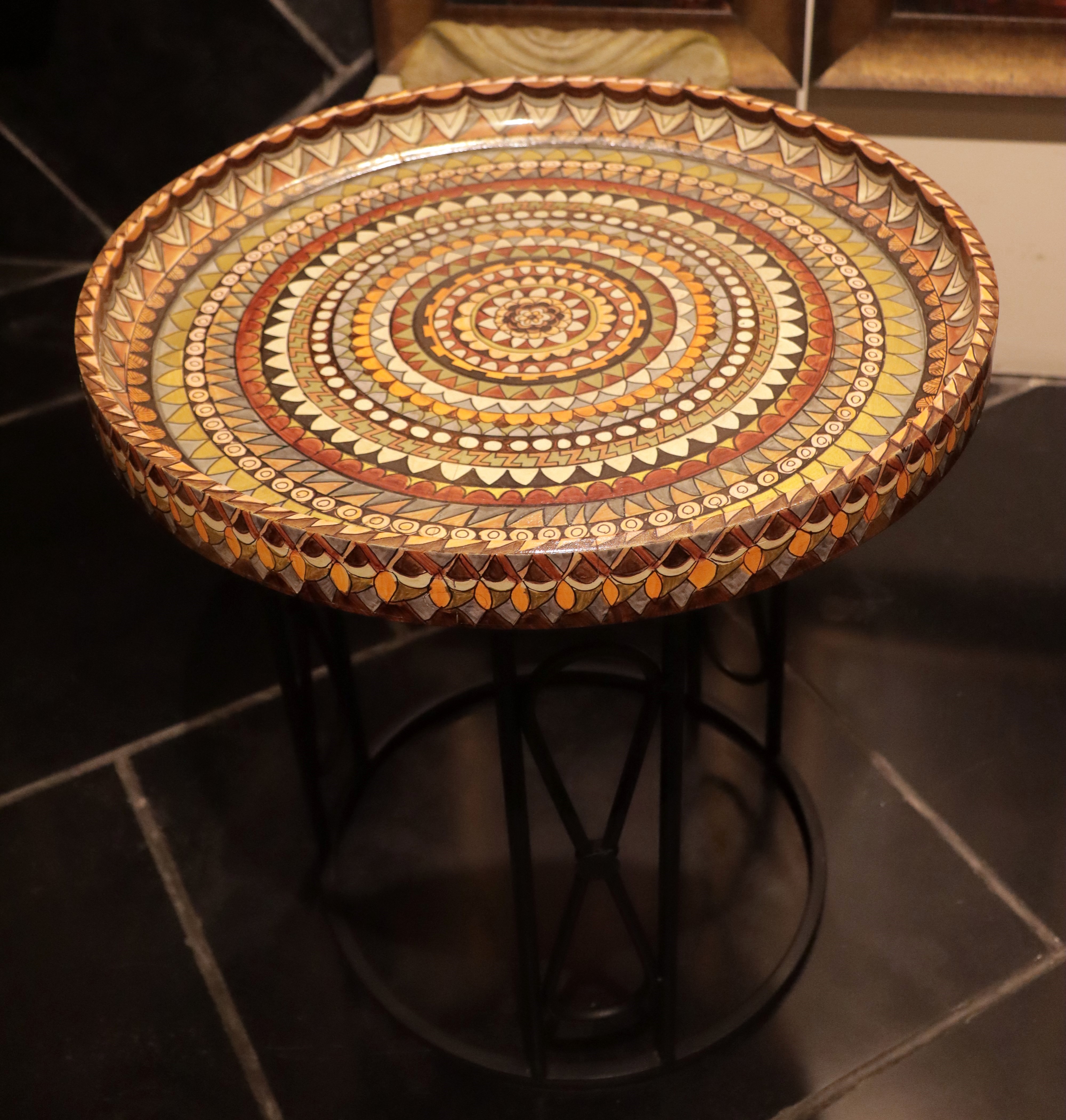 Titled Sacred Circles, this artwork by Anju Kumar has a mandala made on a wooden table and mounted on a wrought-iron stand to function as a coffee table.