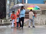 People walk with umbrellas during rain in Mandi on Sunday. (Birbal Sharma/HT)