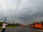 Gram it: A passerby attempts to get the perfect scenic shot as clouds hover over India Gate area after rain brought some cool to the city on Monday morning.  