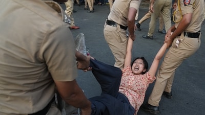 A protester is detained by police during a protest demanding the resignation of Gyanesh Kumar.