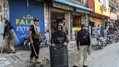 Police personnel stand guard along a street after the imposition of an emergency rule in Peshawar on October 12. (AFP)