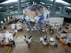 Attendees sit under a globe in a lobby at the side events pavilions at the COP30 U.N. Climate Summit, Tuesday, Nov. 11, 2025, in Belem, Brazil. (AP Photo/Fernando Llano)