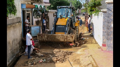 An earthmover clears mud and debris from a street following flash floods in the Muthi Dream City area in Jammu on Monday. (PTI)