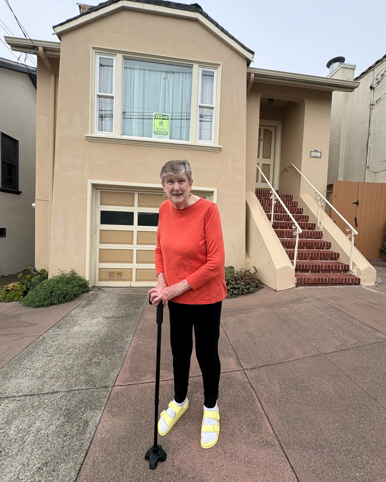 Joanie Landon in front of her house with a ‘Yes on G‘ sign in the window.