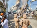An agitated mob torched a chemist shop which was demolished by Mansa district authorities on Wednesday. The shop belonged to Ashwani Kumar, where he fatally shot Parvinder Singh Jhota on Tuesday morning. (HT Photo)