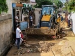 An earthmover clears mud and debris from a street following flash floods in the Muthi Dream City area in Jammu on Monday. (PTI)