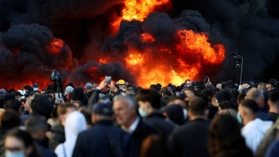 People gather near a fire as plumes of black smoke rise, amid an anti-government protest by students, in Tirana, Albania, (REUTERS)