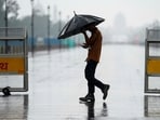 A man makes his way amid rainfall, at India Gate, in New Delhi, Thursday,