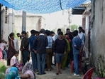 Local residents gather outside the deceased family’s home in a Greater Noida village.