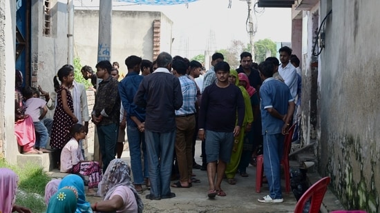 Local residents gather outside the deceased family’s home in a Greater Noida village. (Sunil Ghosh/HT)