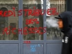 A man walks next to graffiti, which says "Redistribute wealth", on a shop window, the day after clashes during a national day of demonstrations against the cost of living and rising fuel prices, in Marseille, France, October 18, 2026. REUTERS/Manon Cruz