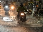 Commuters in Chennai navigate a waterlogged road amid heavy rain during the northeast monsoon.