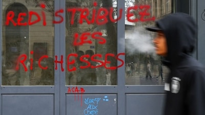 A man walks next to graffiti, which says "Redistribute wealth", on a shop window, the day after clashes during a national day of demonstrations against the cost of living and rising fuel prices, in Marseille, France, October 18, 2026. REUTERS/Manon Cruz (REUTERS)