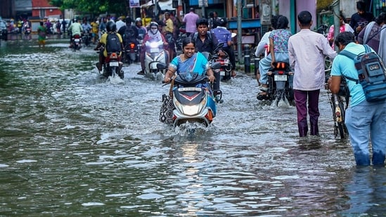 Commuters wade through a waterlogged street following heavy rain, in Chennai, Sunday, Oct. 18, 2026.
