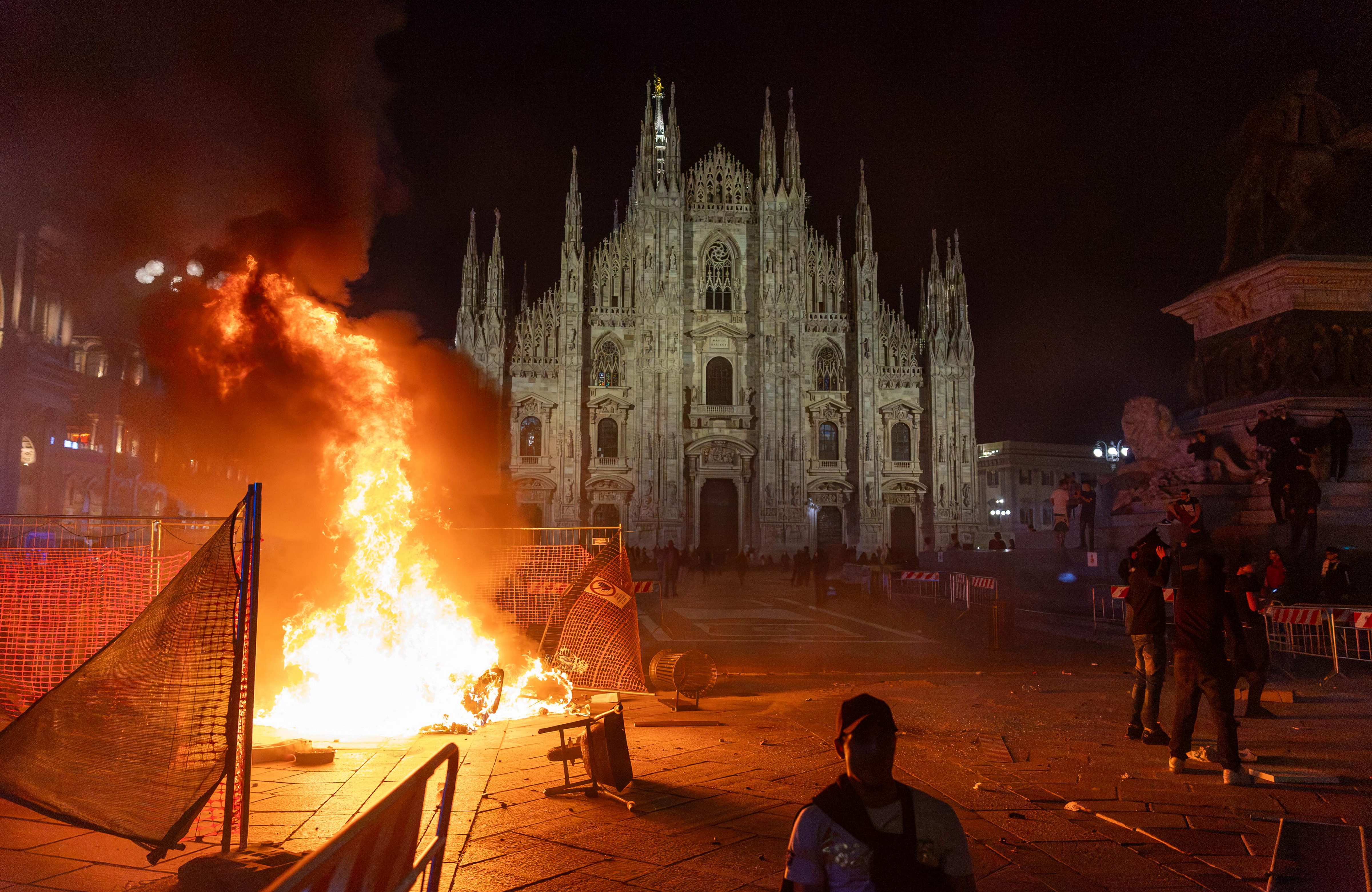 A fire burns following clashes between police and "Italia in Piazza" protesters in front of the Milan Cathedral in Milan, Italy, on Saturday. (AP)