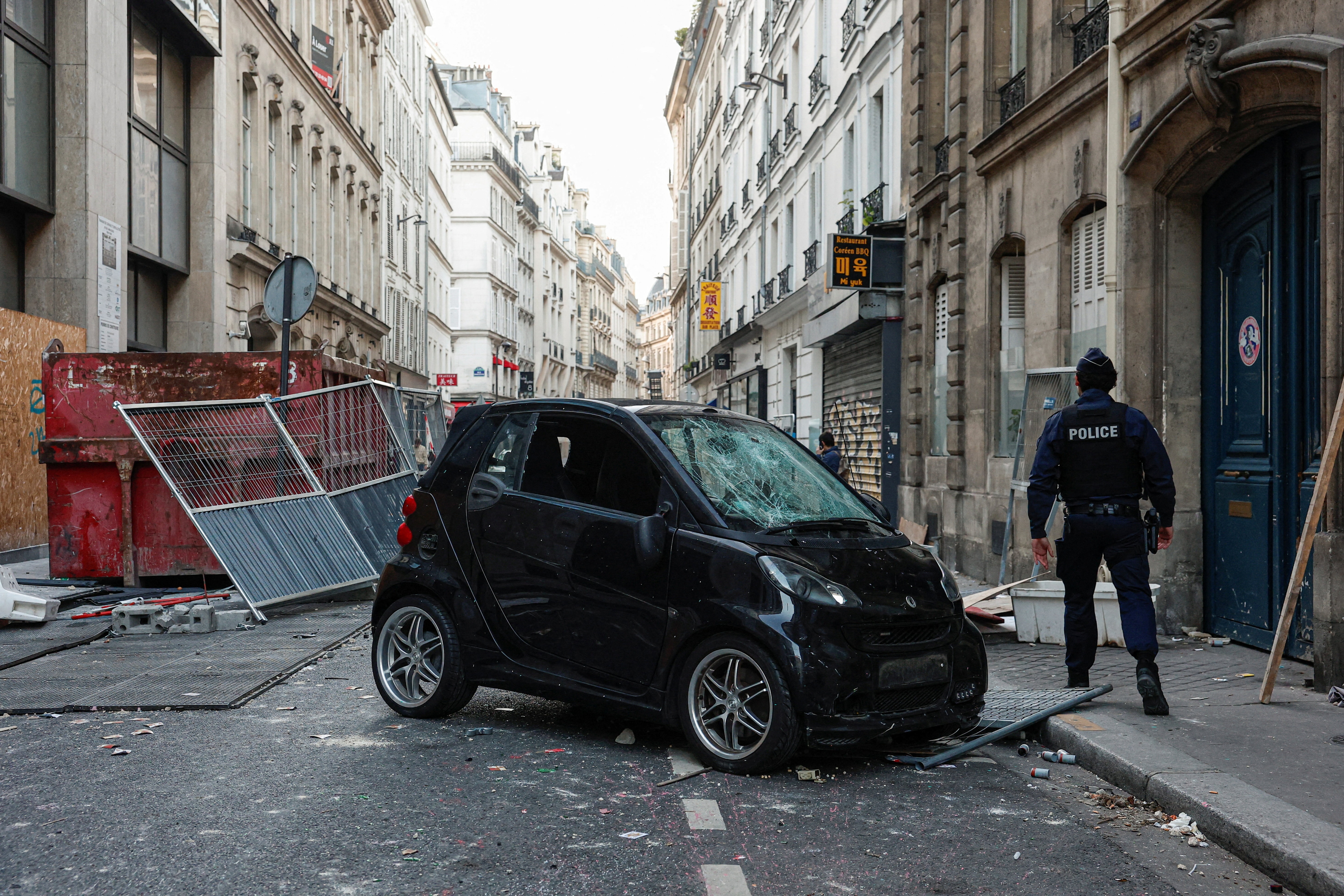 A police officer walks past a vandalised car a day after clashes during a national day of demonstrations in Paris on October 18, 2026. (Reuters)