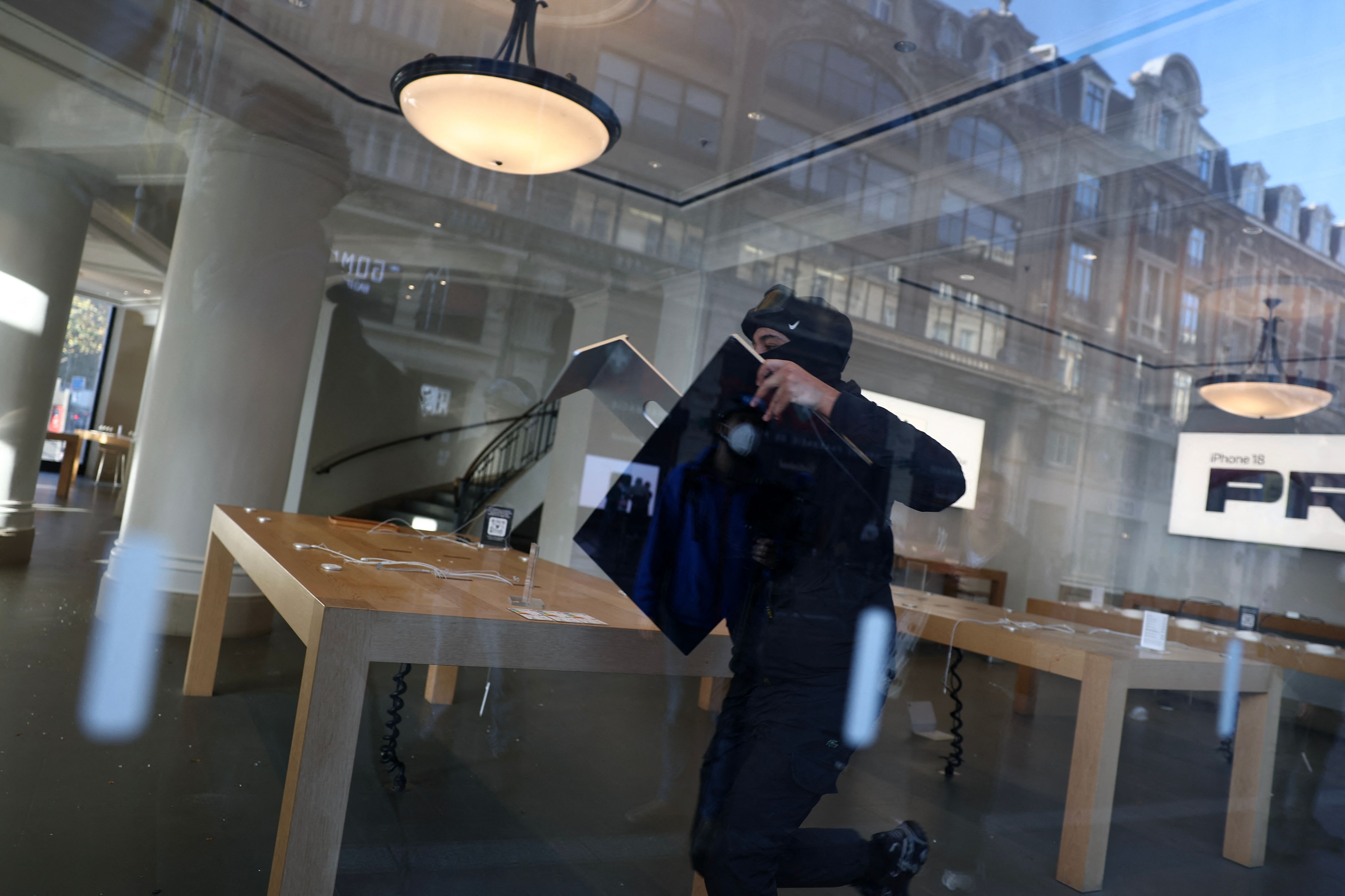 A protester steals an Apple screen at the Apple Store which has been ransacked during ongoing protest action against the "high cost of living", in Lille, northern France, on October 17. (AFP)