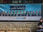 A woman sits near a pre-election campaign banner featuring leaders of the Joint List, ahead of Israel's national election, in Nazareth, Israel October 10. 