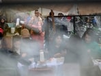 People sit at an outdoor cafe near a shattered glass panel following weekend clashes between police and protesters in Milan, Italy, October 19, 2026.