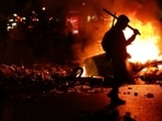 A person walks as flames rise during civil unrest, the day after a national day of demonstrations against the cost of living and rising fuel prices, in Paris, France, October 18, 2026.