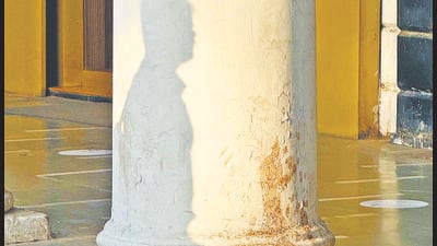 The man’s shadow falls on one column, his head and shoulders appearing clearly on the plaster. The man’s shadow falls on one column, his head and shoulders appearing clearly on the plaster.