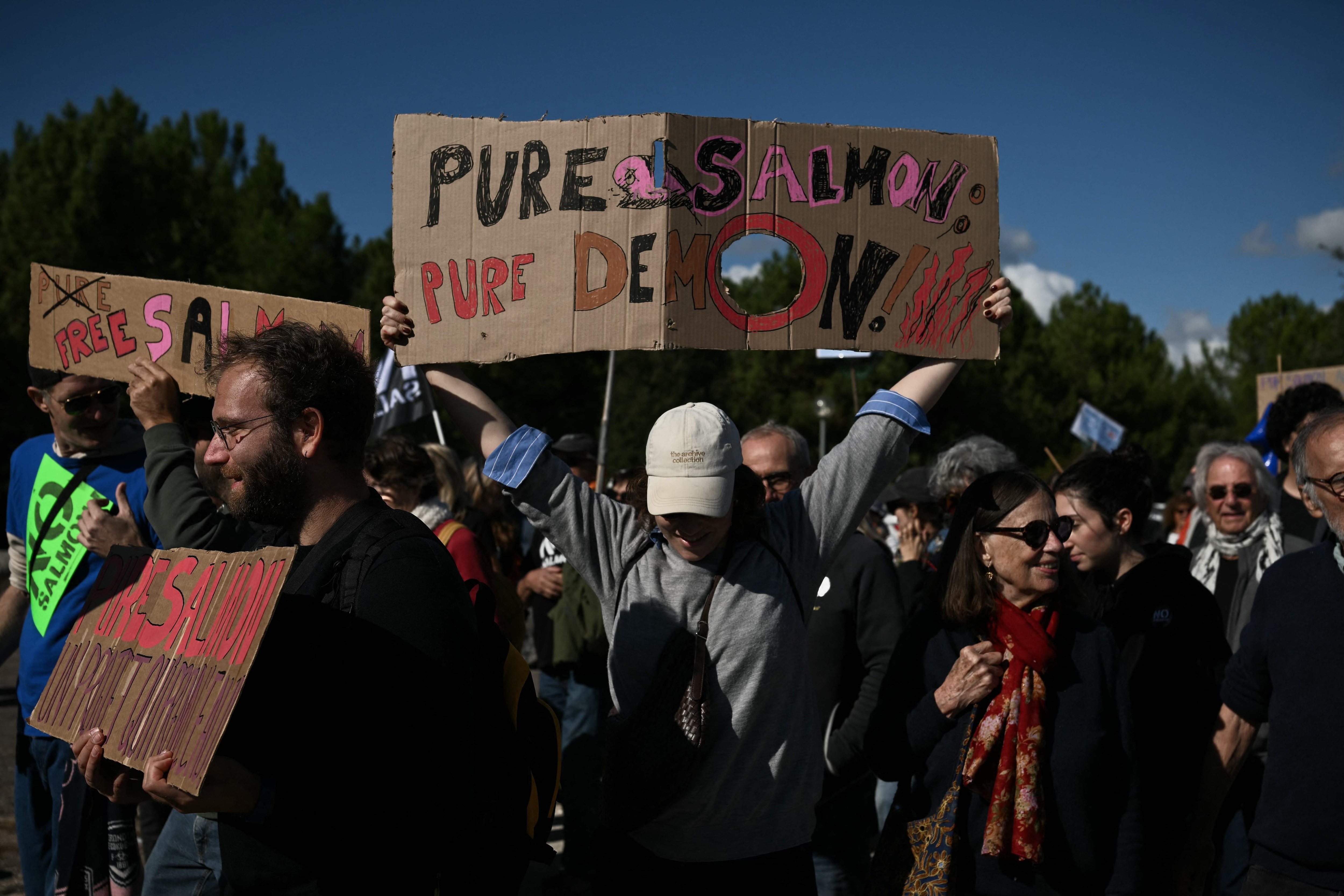 Protesters hold placards while taking part in a demonstration against the planned Pure Salmon land-based industrial salmon farm set to produce 10,000 tonnes of salmon per year at the tip of the Gironde estuary, in Le Verdon-sur-Mer, southwestern France, on October 18, 2026. (Photo by Philippe LOPEZ / AFP) (AFP)