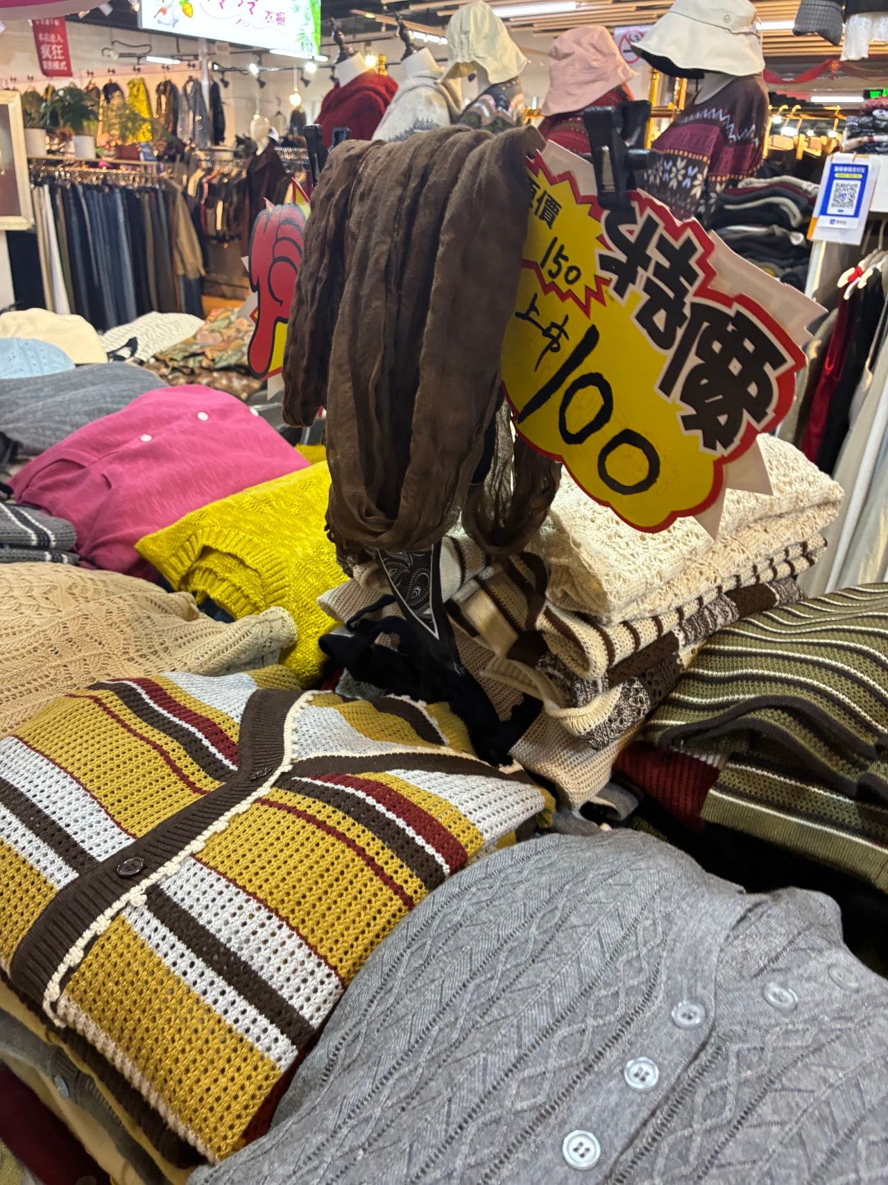 Li Yan, a clothing vendor at Daliushu Market in Beijing, sells sweaters for the equivalent of around <img src=