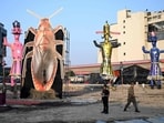 Security personnel stand guard beside an effigy of a cockroach.