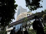 Men walk past a screen displaying market results outside the Bombay Stock Exchange (BSE) in Mumbai