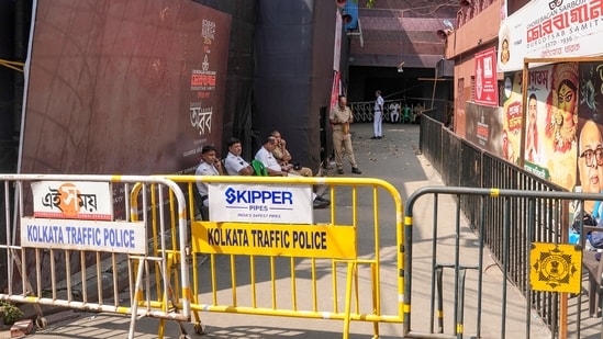 Police personnel sit outside the Chorbagan Sarbojanin Durga Puja pandal following a recent stampede-like situation, in Kolkata, Monday, Oct. 19, 2026.